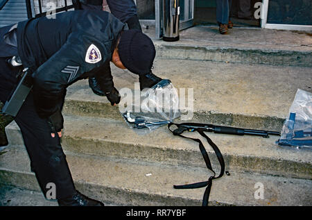 Prince Georges County, Maryland. USA, 1988 Prince Georges County officer schaut über die Waffen gefunden, die an einem Tatort Sinn Stockfoto