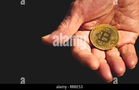 Bitcoin Gold in den älteren Mann die Hand auf dunklem Hintergrund. bitcoin Bonus Stockfoto