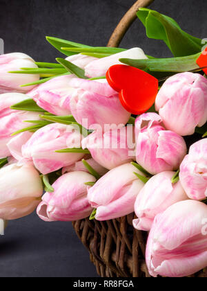 Riesige Bouquet von rosa Tulpen im Weidenkorb. Postkarte Motiv, Kopieren, mit dekorativen rotes Herz, Tag der Frau am 8. März Stockfoto