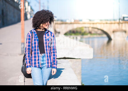 Hipster schöne fröhliche junge schwarze Mädchen zu Fuß inder Stadt Genießen der Freizeit im Freien in der Nähe eines Flusses - Student mit Rucksack der sp genießen Stockfoto