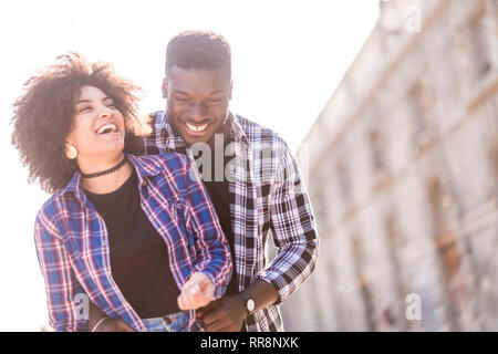 Gerne schwarze afrikanische Mixed Race Paar Lachen und Genießen der Beziehungen und der Freundschaft, die zusammen mit dem Sonnenlicht im Gegenlicht - Outdoor Freizeitaktivitäten Stockfoto