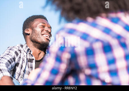 Schwarz afro junger Mann lachen viel im Freien - hübscher Kerl Lachen und Spaß mit Freundin von hinten gesehen - frohe und glückliche Menschen - mit Außengewinde Stockfoto