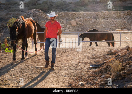 Red Shirt cowboy farmer Mann bei der Arbeit mit Pferden im freien Land Ort - schöne Alternative freien Lebensstil für Menschen genießen die Natur und die Stockfoto