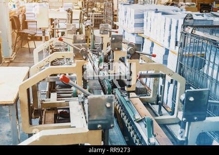 Maschine für das Zusammenfügen von Blatt Papier im Druck. Zeitschrift, Broschüre, Buch. Produktion von Druckerzeugnissen. Vintage-Technologie Stockfoto