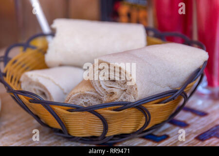 Afrikanische Speisen. Walzen der Injera - ein sauerteig Fladenbrot aus teff Mehl gemacht. Es ist dem nationalen Gericht aus Äthiopien, Eritrea, Somalia und Dschibuti Stockfoto