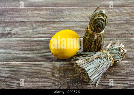 Organische chemische Zitronengras (Cymbopogon Flexuosus) in Bündeln und Zitrone Obst auf einem Holztisch. Kräuter für Tee. Stockfoto