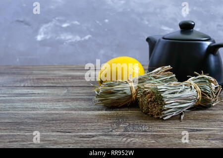 Organische chemische Zitronengras (Cymbopogon Flexuosus) in Bündeln und Zitrone Obst auf einem Holztisch. Kräuter für Tee. Stockfoto