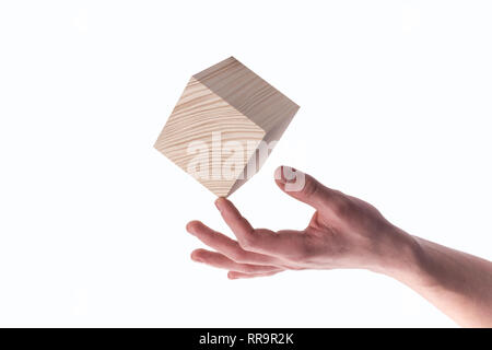 Hand hält einen Würfel. Holzwürfel balancing in den Finger. Stockfoto