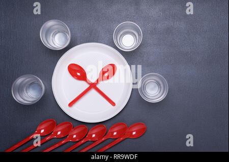 Einmalgeschirr Teller und Löffel. Plastik kontaminiert die Erde und Wasser. Konzept der Umweltverschmutzung. Ansicht von oben. Stockfoto