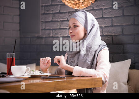 Junge muslimische Frau in Cafe mit ihrem Freund sitzt und spricht Stockfoto