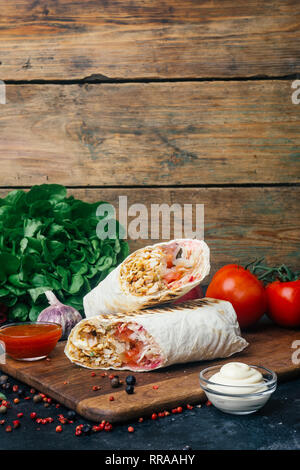 Döner Kebab (shawarma oder Döner wrap). Gegrilltes Hähnchen auf LAVASH (Fladenbrot) mit frischem Gemüse - Tomaten, grüner Salat, Paprika. Alte hölzerne backgr Stockfoto