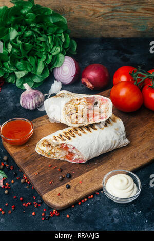 Döner Kebab (shawarma oder Döner wrap). Gegrilltes Hähnchen auf LAVASH (Fladenbrot) mit frischem Gemüse - Tomaten, grüner Salat, Paprika. Alte hölzerne backgr Stockfoto