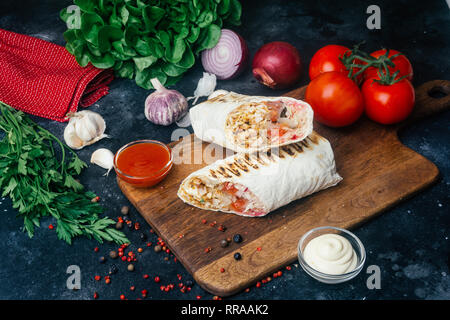 Döner Kebab (shawarma oder Döner wrap). Gegrilltes Hähnchen auf LAVASH (Fladenbrot) mit frischem Gemüse - Tomaten, grüner Salat, Paprika. Alte hölzerne backgr Stockfoto