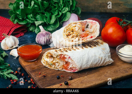 Döner Kebab (shawarma oder Döner wrap). Gegrilltes Hähnchen auf LAVASH (Fladenbrot) mit frischem Gemüse - Tomaten, grüner Salat, Paprika. Alte hölzerne backgr Stockfoto