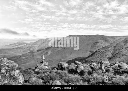 TANKWA KAROO NATIONAL PARK, SÜDAFRIKA, 31. AUGUST 2018: ein Tourist am Aussichtspunkt in der Gannaga Pass in der Tankwa Karoo in Südafrika. Monochr Stockfoto