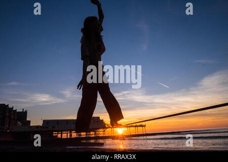 Aberystwyth, Wales. 25. Feb 2019. UK Wetter: heißesten Februar auf Aufzeichnung in Großbritannien in Ceredigion, tagsüber Temperaturen von über 20 Grad. Studenten auf einem slack Line und Royal Pier. Sonnenuntergang Aberystwyth, Ceredigion, Wales, Großbritannien Quelle: Paul Quayle/Alamy leben Nachrichten Stockfoto