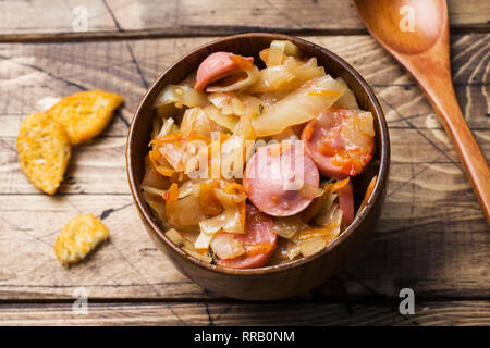 Gedünstetem Rosenkohl mit Würstchen in hölzernen Schüsseln auf den Tisch. Selektiver Fokus Stockfoto
