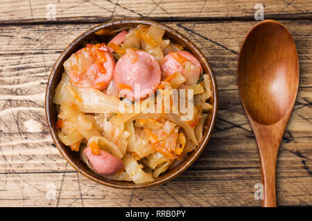 Gedünstetem Rosenkohl mit Würstchen in hölzernen Schüsseln auf den Tisch. Selektiver Fokus Stockfoto