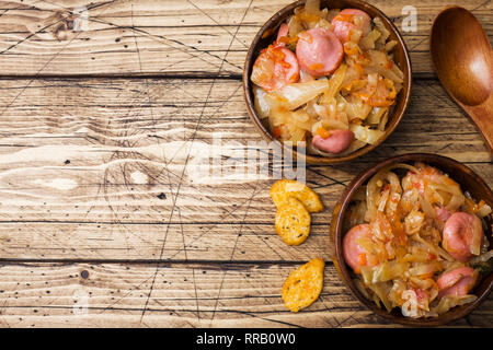 Gedünstetem Rosenkohl mit Würstchen in hölzernen Schüsseln auf den Tisch. Selektiver Fokus Stockfoto