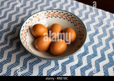 Schüssel Eier, 5 braune Eier in eine Schüssel geben. Stockfoto