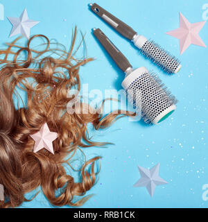 Haarpflege, lange schöne Haare und Kämmen, Kämmen, starken gesunden Wurzeln. Haare liegen auf blauem Hintergrund. Friseur und Zubehör, perfekte Frisur. Stockfoto