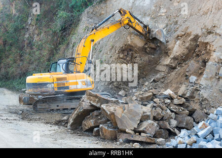 Ein Bagger gräbt und sammelt die Erde und Stein für eine Straße Ausbau Stockfoto