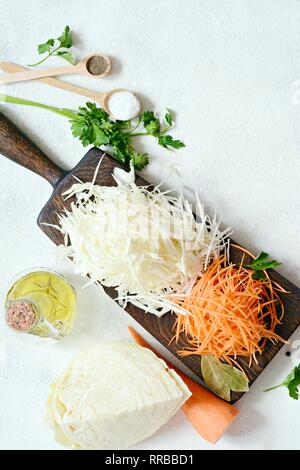 Slicing frischen Kohl und Möhren auf einem Holzbrett auf einem hellen Hintergrund. Gemüse für Gären, für lange Gärung. Sortiment an frischen vegetabl Stockfoto