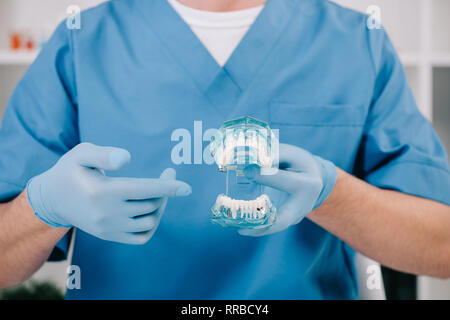 7/8-Ansicht von Kieferorthopäden zeigt mit dem Finger auf Spannbacken in der Klinik Stockfoto