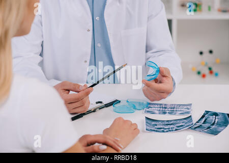 7/8-Ansicht von Kieferorthopäden auf Trainer Zahnspangen in Absprache mit Frau in Klinik Stockfoto