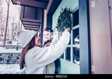 Lächelnd Freundin tragen warmer Mantel, Kranz an der vorderen Klappe Stockfoto