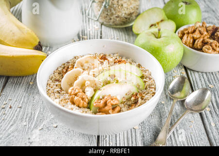 Gesundes Frühstück Müsli mit Nüssen ad Früchte - Apfel, Banane, Walnüsse, mit Milch auf hölzernen Background Copy space Stockfoto