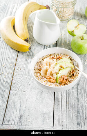 Gesundes Frühstück Müsli mit Nüssen ad Früchte - Apfel, Banane, Walnüsse, mit Milch auf hölzernen Background Copy space Stockfoto