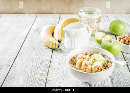 Gesundes Frühstück Müsli mit Nüssen ad Früchte - Apfel, Banane, Walnüsse, mit Milch auf hölzernen Background Copy space Stockfoto