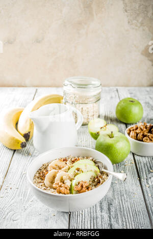 Gesundes Frühstück Müsli mit Nüssen ad Früchte - Apfel, Banane, Walnüsse, mit Milch auf hölzernen Background Copy space Stockfoto