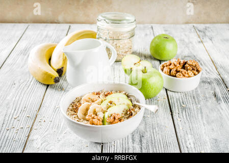 Gesundes Frühstück Müsli mit Nüssen ad Früchte - Apfel, Banane, Walnüsse, mit Milch auf hölzernen Background Copy space Stockfoto