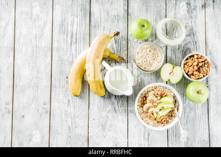 Gesundes Frühstück Müsli mit Nüssen ad Früchte - Apfel, Banane, Walnüsse, mit Milch auf hölzernen Background Copy space Stockfoto