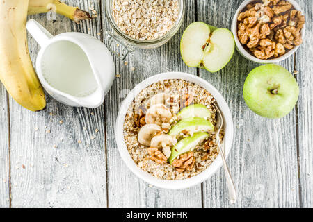 Gesundes Frühstück Müsli mit Nüssen ad Früchte - Apfel, Banane, Walnüsse, mit Milch auf hölzernen Background Copy space Stockfoto