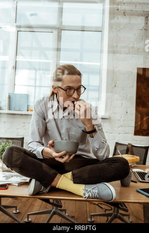 Netter intelligenter Mann hält eine Schüssel mit Popcorn Stockfoto