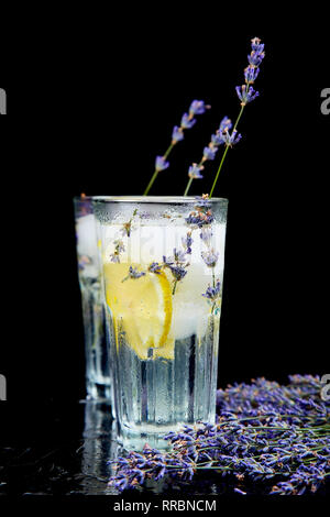 Lavendel Limonade mit Zitrone und Eis auf schwarzen Hintergrund. Detox Wasser. Im Sommer trinken. Ernährung Cocktail. Schön. Stockfoto