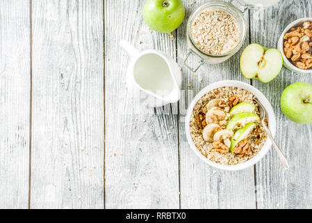 Gesundes Frühstück Müsli mit Nüssen ad Früchte - Apfel, Banane, Walnüsse, mit Milch auf hölzernen Background Copy space Stockfoto