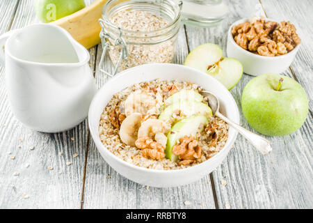 Gesundes Frühstück Müsli mit Nüssen ad Früchte - Apfel, Banane, Walnüsse, mit Milch auf hölzernen Background Copy space Stockfoto