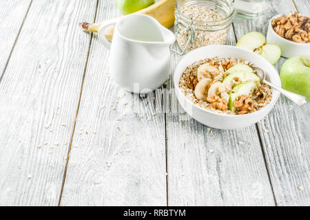 Gesundes Frühstück Müsli mit Nüssen ad Früchte - Apfel, Banane, Walnüsse, mit Milch auf hölzernen Background Copy space Stockfoto