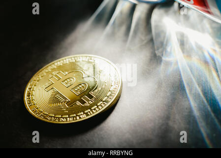 Bitcoin physische Münzen durch Lichtstrahlen mit dunklem Hintergrund beleuchtet. Stockfoto