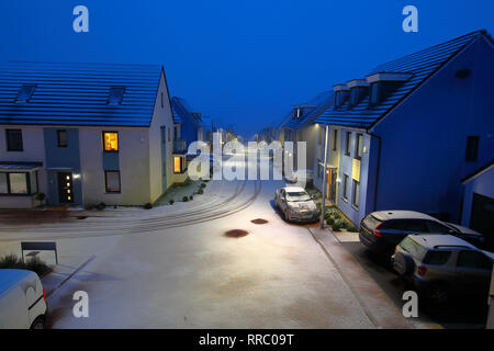 Sie suchen eine Straße in Richtung Meer mit neuen Schnee fallen und die Cloud zusammenführen zu Mit dem Meer auf eine Winter Abend in einer quiete Gehäuse ländlichen Anwesen. Stockfoto