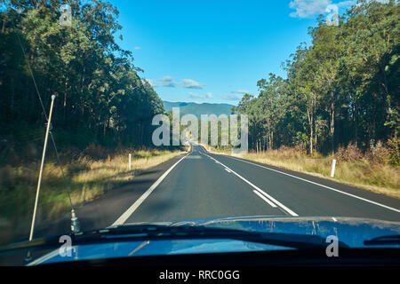 Ansicht von innen ein Auto entlang einer Straße Reisen mit Gummi Bäume auf beiden Seiten im australischen Outback auf einem hellen Tag mit kein anderer Datenverkehr Insight Stockfoto