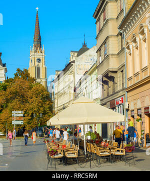 NOVI SAD, Serbien - 26. AUGUST 2017: Menschen bei Street Restaurant in Novi Sad. Der Name unserer Kirche im Hintergrund. Novi Sad ist die zweite Lar Stockfoto