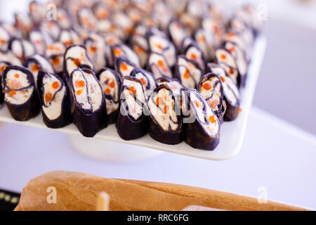 Rollen schwarz Pfannkuchen mit Käse, Lachs und roter Kaviar auf die weiße Platte, schöne Präsentation. Stockfoto