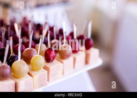 Leichte Snacks in einer Platte auf einem Buffet. Sortiert mini Canapes, Köstlichkeiten und Snacks, Essen im Restaurant an der Veranstaltung. Rote Trauben, Käse und Schinken. Stockfoto