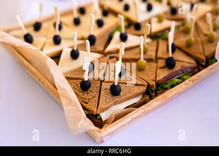 Nahaufnahme einer Club Sandwich. Sandwich mit Schinken, Schinken, Salat, Gemüse, Salat und Oliven auf einer frischen in Scheiben Roggenbrot auf hölzernen backgro Stockfoto