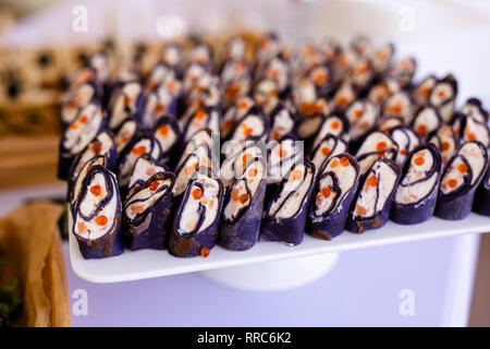 Rollen schwarz Pfannkuchen mit Käse, Lachs und roter Kaviar auf die weiße Platte, schöne Präsentation. Stockfoto